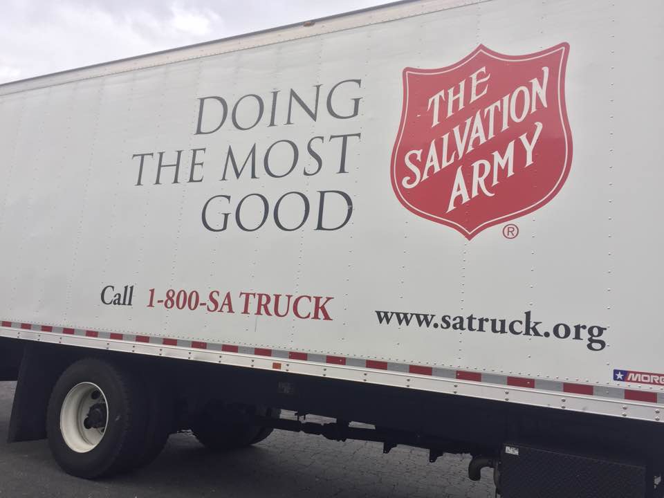 The side of a Salvation Army collection truck with its red shield emblem.