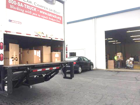 Boxes loaded in a Salvation Army truck beside a warehouse.